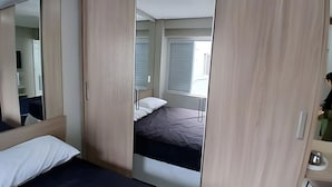 Un dormitorio con cama, armario y espejo.