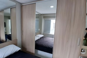 A bedroom with a bed, a wardrobe, and a mirror. - SHB - Apê Charmoso no Embaré (Santos)