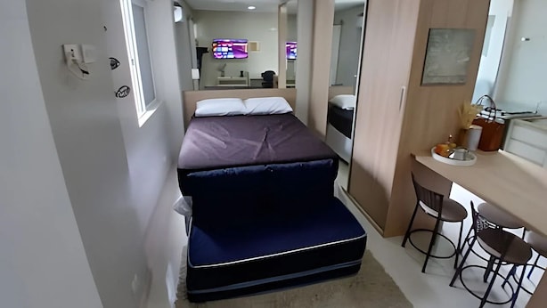 Una habitación de hotel estrecha con una cama, un escritorio y una silla.