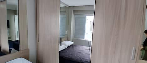 Un dormitorio con cama, espejo y armario.