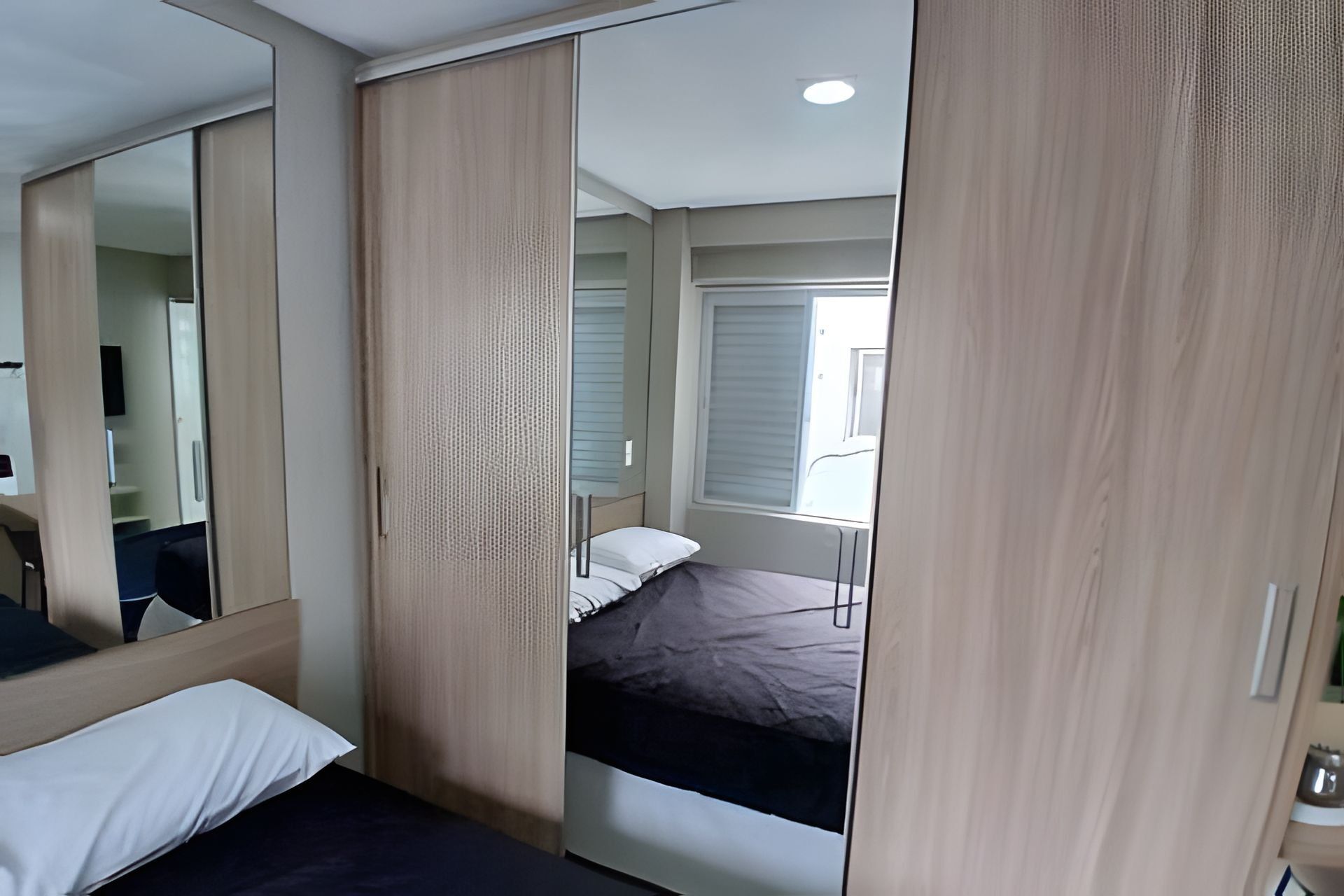 Un dormitorio con cama, espejo y armario.