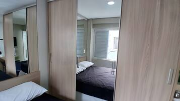 Un dormitorio con cama, espejo y armario.
