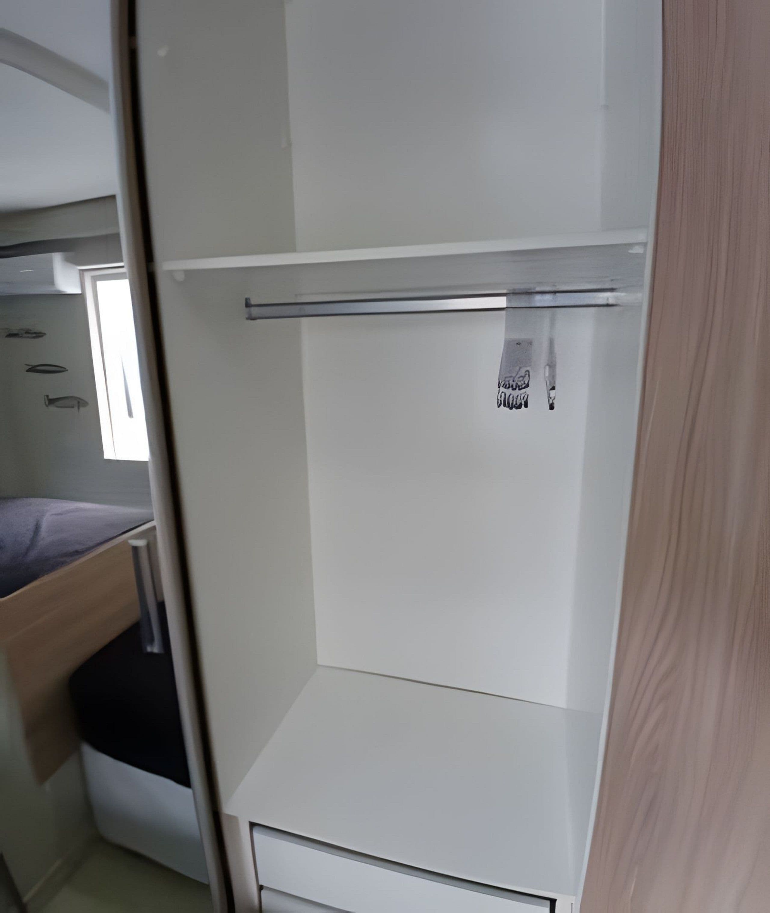 Una habitación pequeña con una cama, un escritorio pequeño y un armario blanco con espejo.