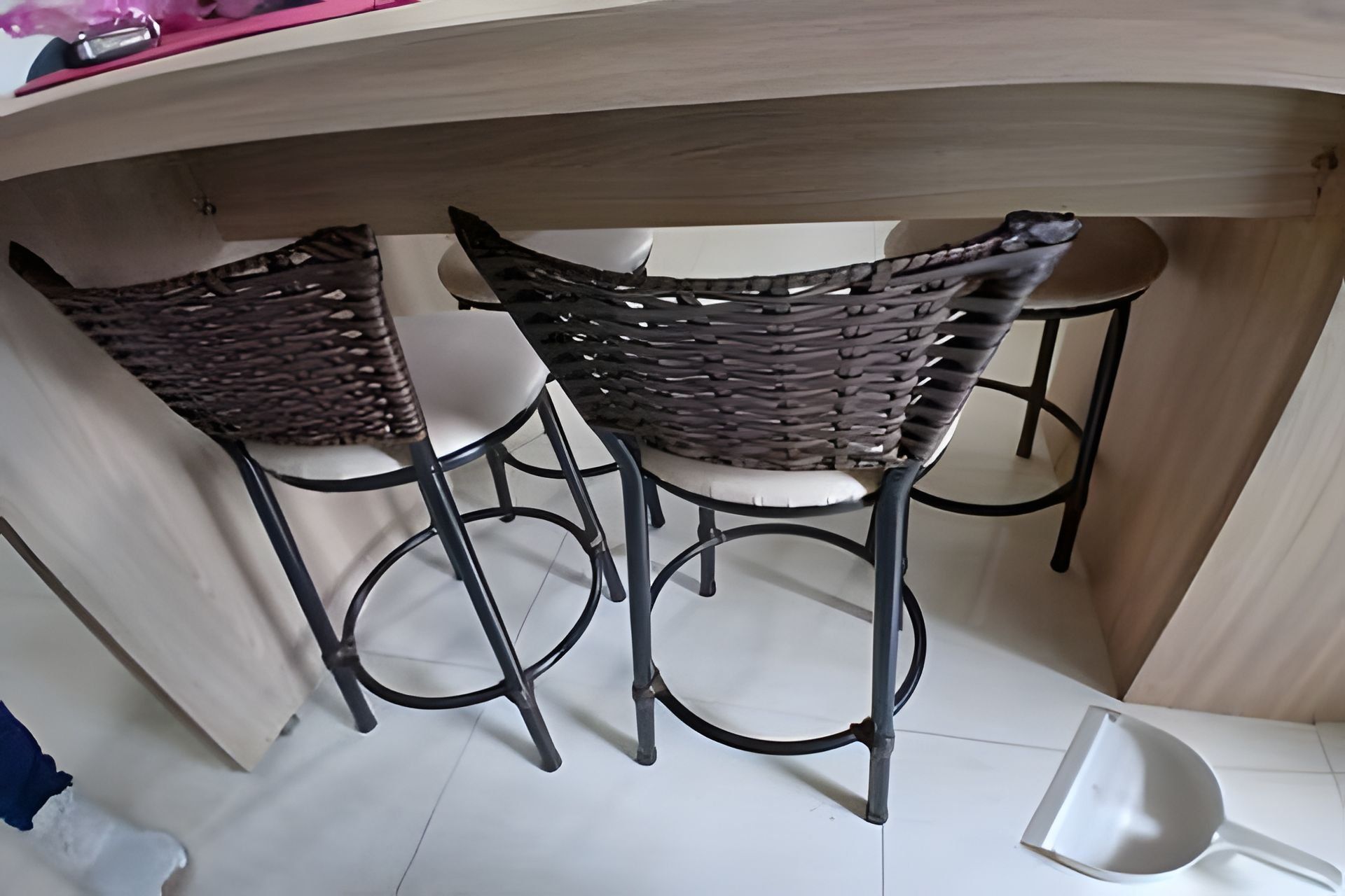 Een bar met twee rieten stoelen en een witte barkruk.