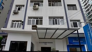 A multi-story building with a modern architectural design, featuring a central entrance with a glass canopy and a sign above it.
