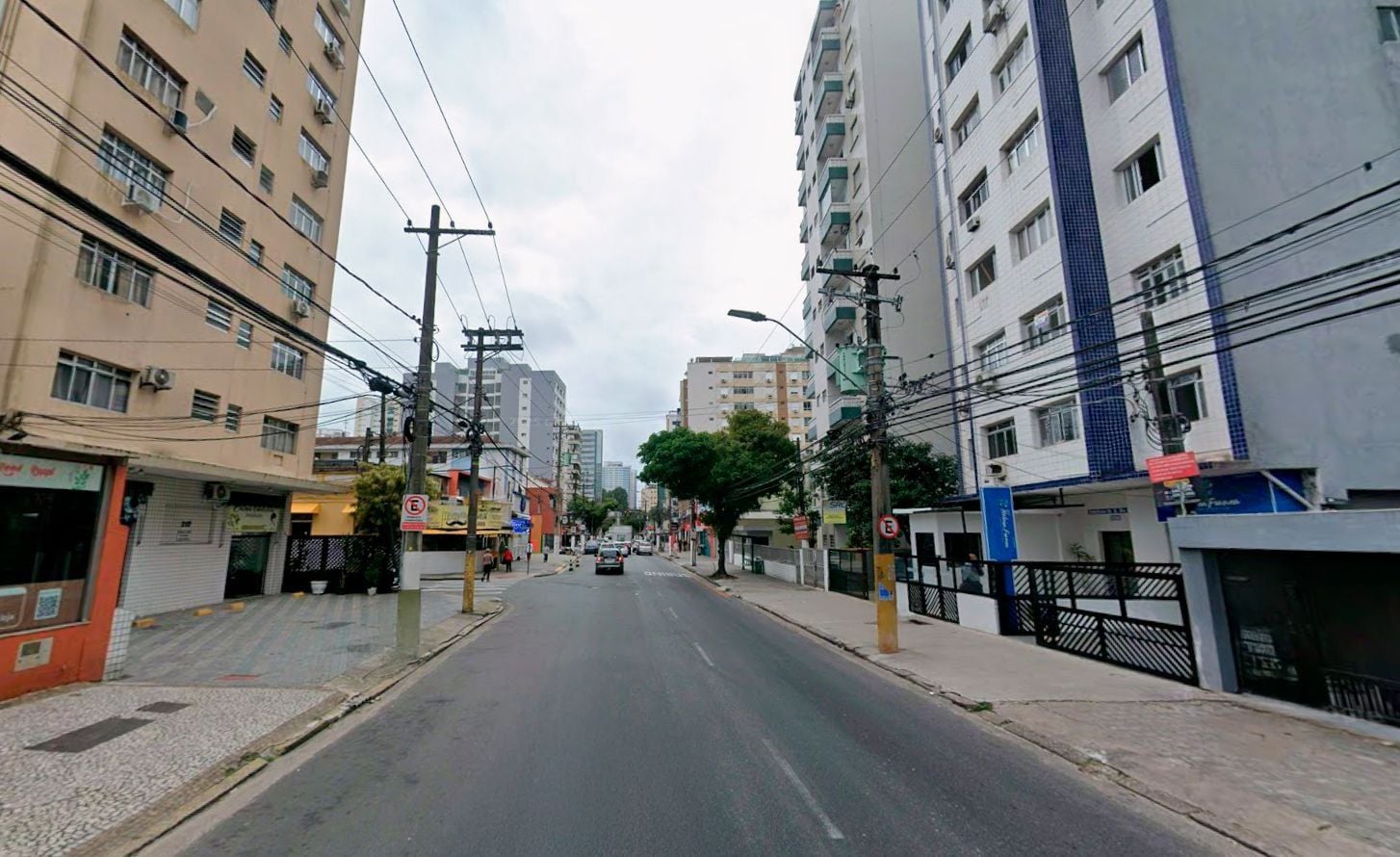 Calle flanqueada por edificios, con tendido eléctrico y cielo despejado.