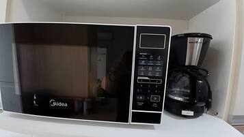 Une cuisine avec un micro-ondes noir et une machine à café posés sur le plan de travail.