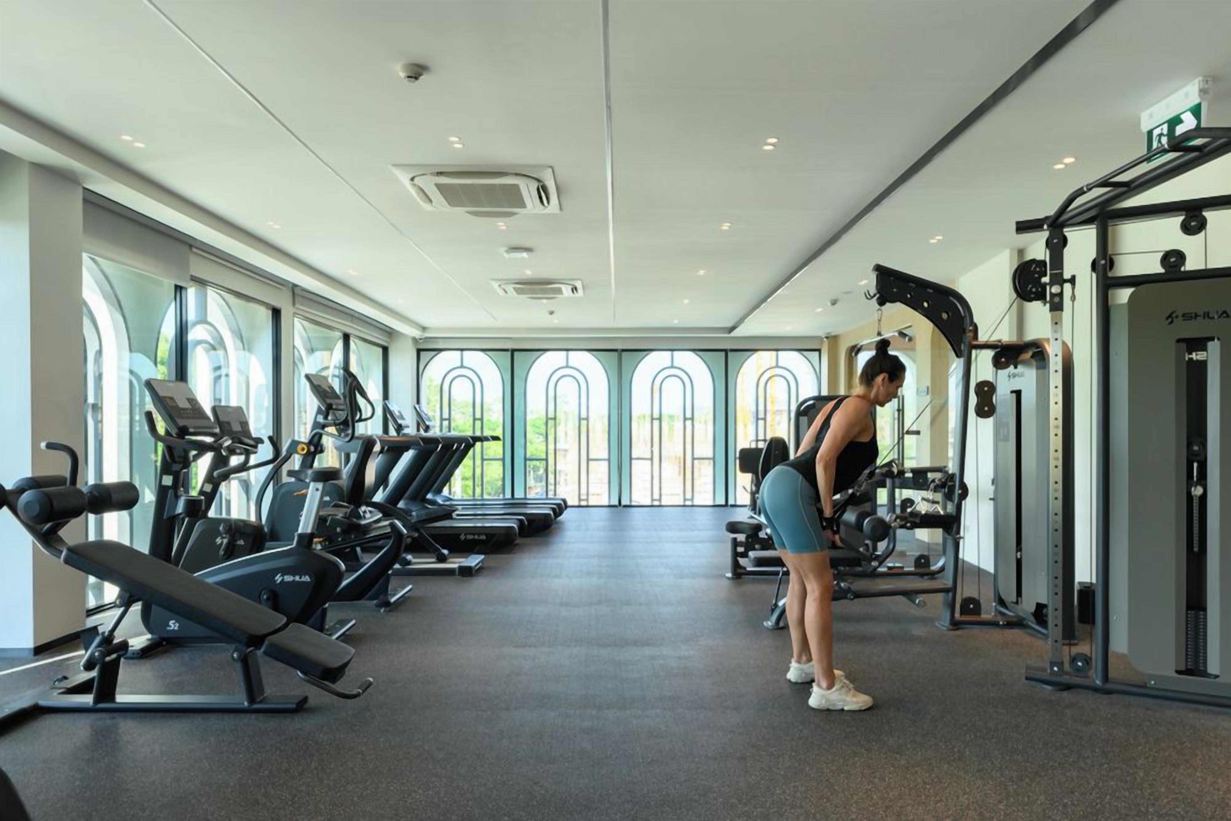 A gym with treadmills, weight machines, and a person exercising.