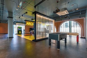 A spacious indoor area with a foosball table, a brightly lit bar area, and a large window providing natural light. - Bang Tao - Tropical Pool & Garden View (Choeng Thale)