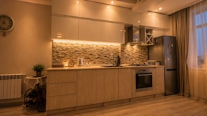 Eine moderne Küche mit Steinrückwand, Holzschränken, einem Edelstahlkühlschrank und einem Gasherd.