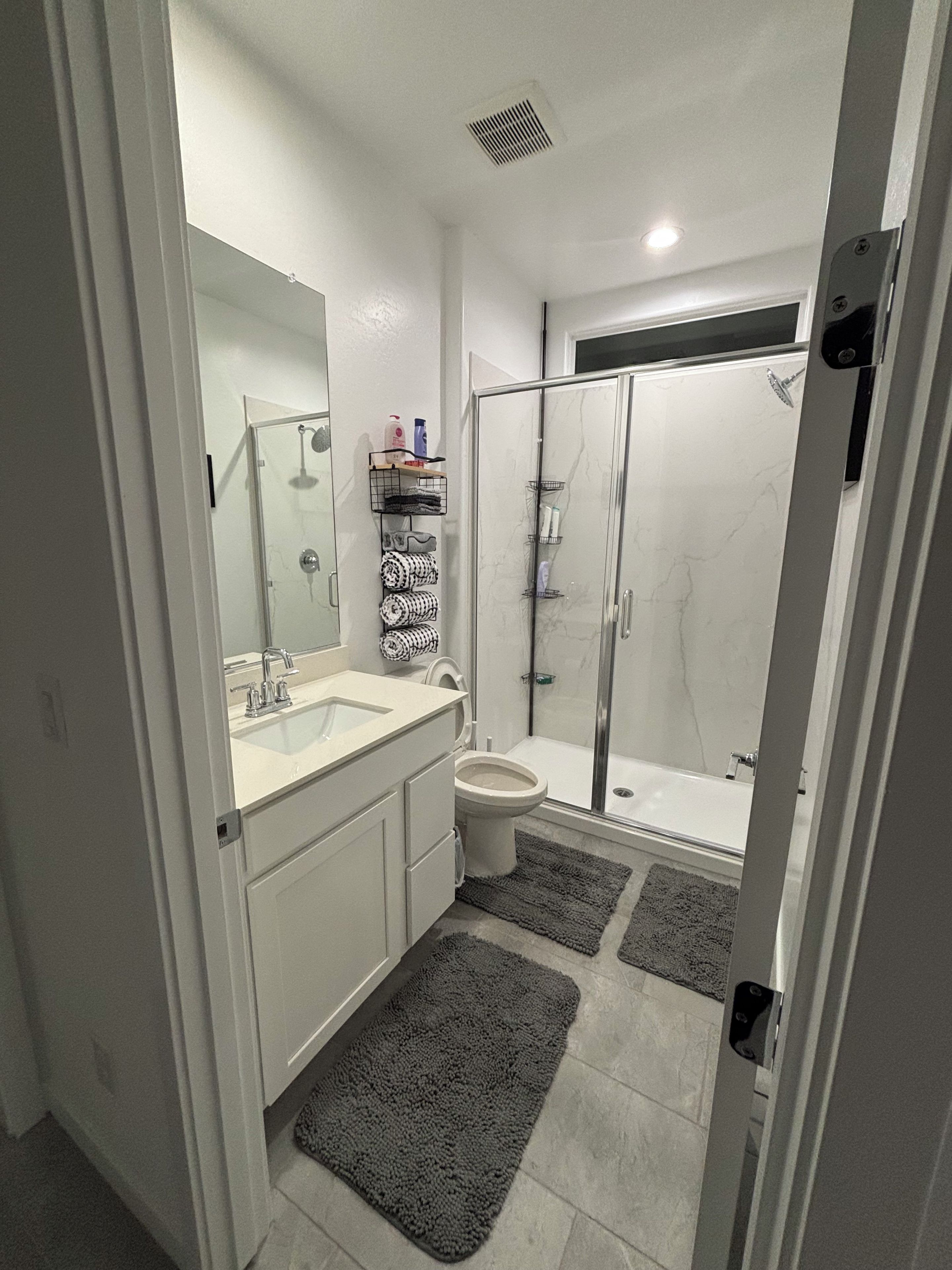 A modern bathroom with a glass shower enclosure, a white sink, and a toilet.