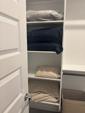 Un armario con estantes que guardan ropa doblada.