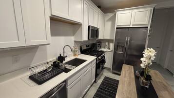 Una cocina moderna con armarios blancos, electrodomésticos de acero inoxidable y una mesa de comedor de madera.