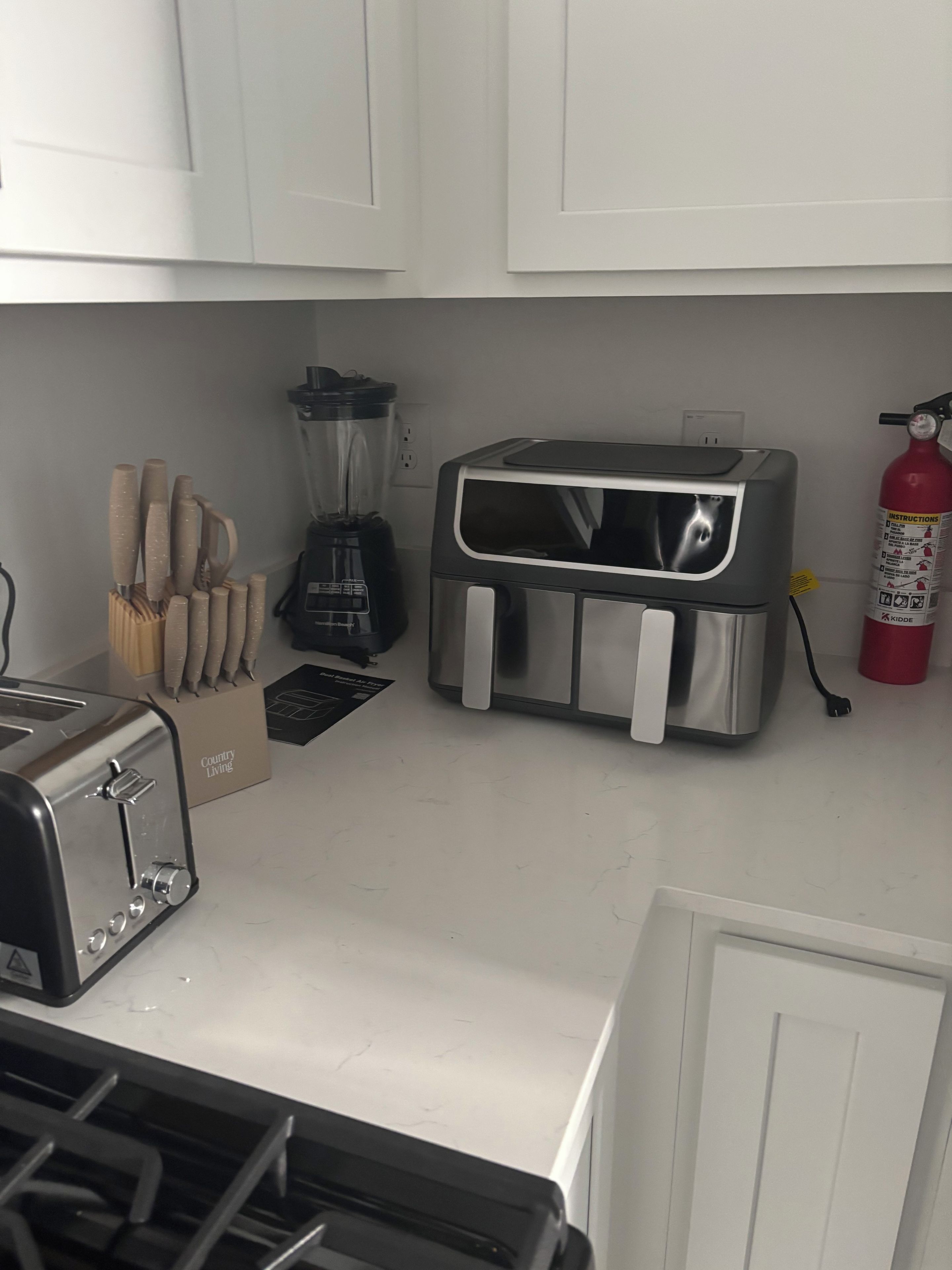 A kitchen with a toaster, a blender, a toaster oven, and a fire extinguisher.