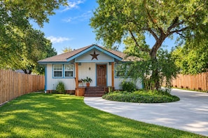A single-story house with a front porch, a star decoration above the door, and a well-maintained lawn. - Spacious 4-bedroom house in peaceful Houston with Fenced Yard! (Houston)