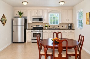 A modern kitchen with stainless steel appliances, white cabinetry, and a dining area with a wooden table and chairs. - Spacious 4-bedroom house in peaceful Houston with Fenced Yard! (Houston)