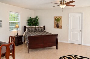 A bedroom with a bed, a ceiling fan, a window with blinds, a plant, a door, and a rug. - Spacious 4-bedroom house in peaceful Houston with Fenced Yard! (Houston)