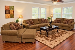 A living room with a sectional sofa, ottoman, coffee table, and two lamps. - Spacious 4-bedroom house in peaceful Houston with Fenced Yard! (Houston)