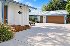 A single-story building with a garage door, a wooden bench, and a concrete driveway. - Spacious 4-bedroom house in peaceful Houston with Fenced Yard! (Houston)