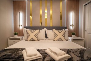 A neatly made bed with pillows and a blanket, bedside tables with small plants, and a wall with vertical light strips. - Luxury 9BR Home Near Disney | Solara Resort 81SA (Kissimmee)