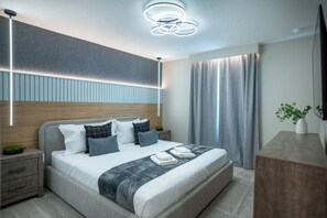 A modern bedroom with a large bed, bedside tables, a desk, and a ceiling light fixture. - Luxury 9BR Home Near Disney | Solara Resort 81SA (Kissimmee)