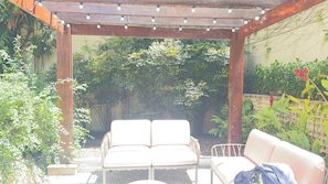 A covered patio with two white chairs, a wooden pergola, and a variety of greenery. - QUALITY SUITES OSCAR FREIRE - 4 STARS - HOSPITAL Clinics and nearby avenue. PAULISTA (São Paulo)
