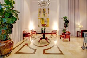 A spacious lobby with a round table, red upholstered chairs, a chandelier, and artwork on the walls. - QUALITY SUITES OSCAR FREIRE - 4 STARS - HOSPITAL Clinics and nearby avenue. PAULISTA (São Paulo)