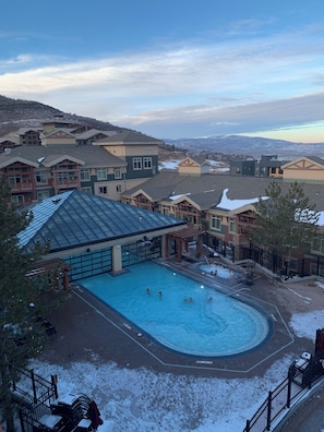 Piscina cercada por edifícios, com vista para colinas cobertas de neve.