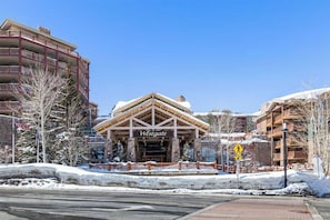 Edifício Westgate com entrada imponente, cercado por terreno e árvores cobertos de neve.