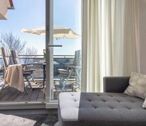 Un balcon avec des meubles d’extérieur, une porte-fenêtre coulissante et une vue sur le ciel.