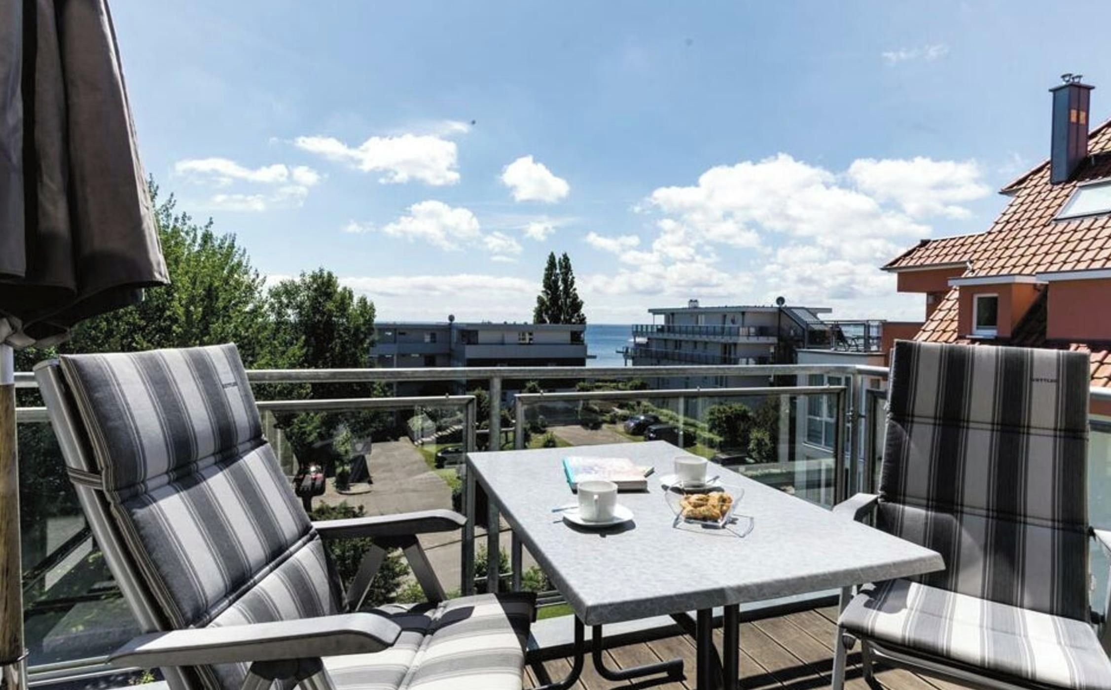 Una terraza con mesa, sillas y vistas al mar y edificios.