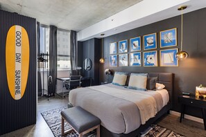 Ein modernes Schlafzimmer mit einem großen Bett, einem Schreibtisch und einem Stuhl. Mehrere gerahmte Bilder zieren die Wand.