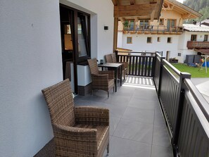 A balcony with wicker furniture, a table, and a view of a mountain. - Modern Holiday Apartment in a Quiet Location (Laengenfeld)