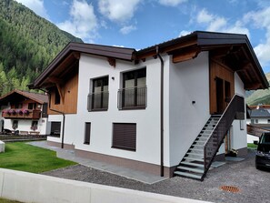 A modern two-story building with a balcony, a staircase, and a view of a forested mountain. - Modern Holiday Apartment in a Quiet Location (Laengenfeld)