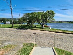Un camino pavimentado que lleva a un parque con un banco y un cartel.