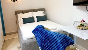 Una camera da letto con un letto, una scrivania, una sedia, una TV e luci a parete.