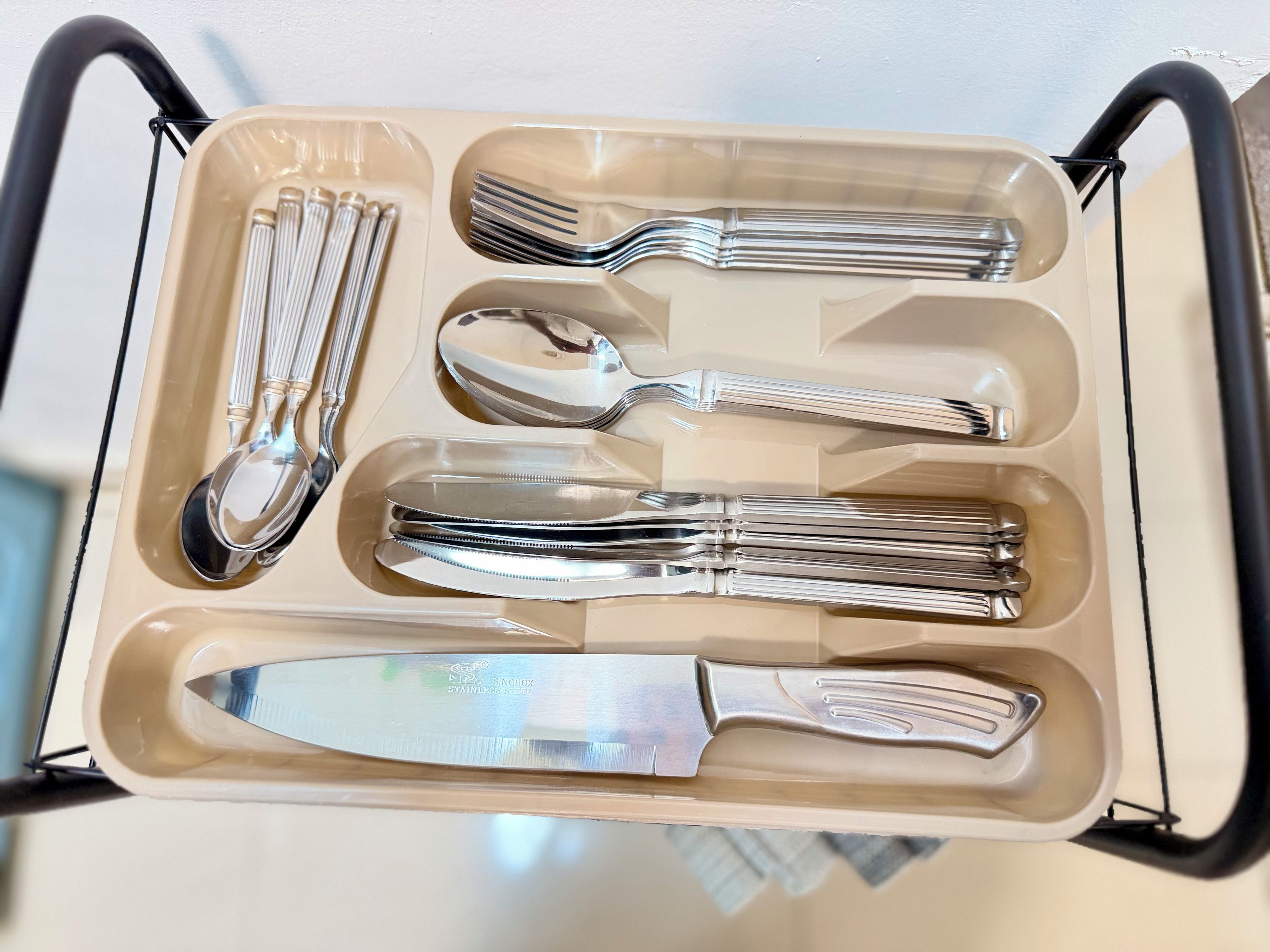Un set di stoviglie in acciaio inossidabile in una scatola beige con manici.
