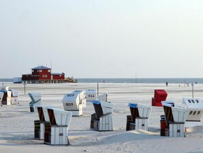 Beach chairs with numbers, a lifeguard tower, and the ocean in the background. - Utholm 12 - Deichblick (St. Peter-Ording)