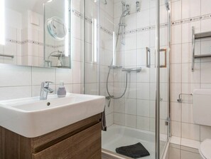A modern bathroom with a glass shower enclosure, a white sink, and a mirror. - Utholm 12 - Deichblick (St. Peter-Ording)