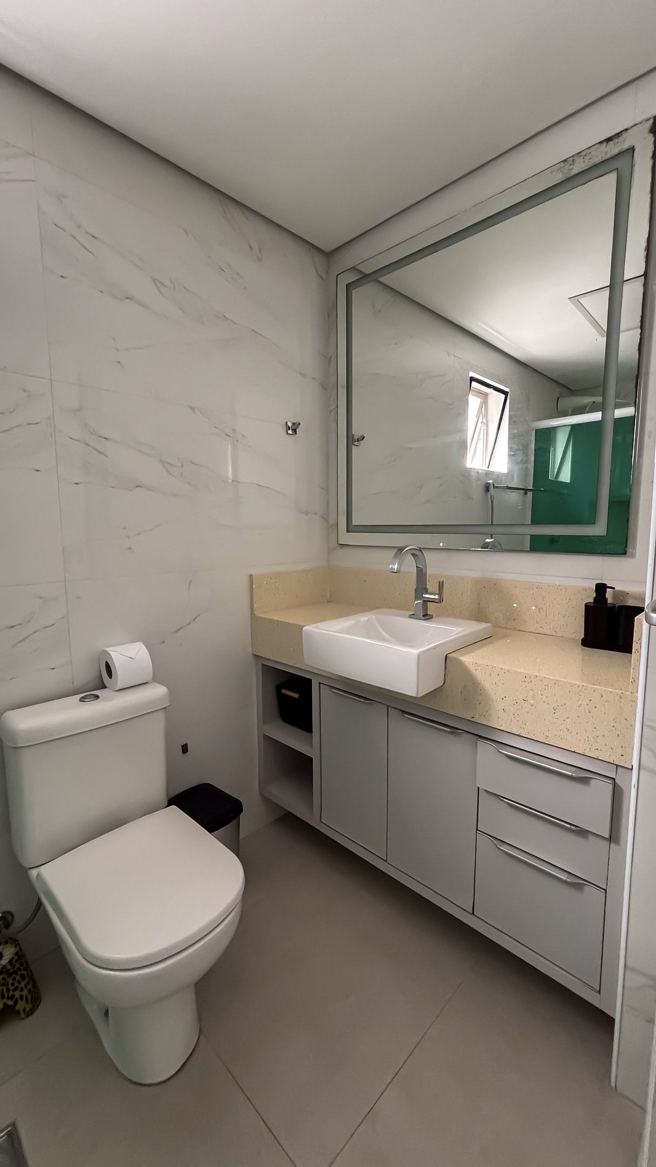 Ein Badezimmer mit Toilette, Waschbecken, Spiegel und Stauraumschrank.