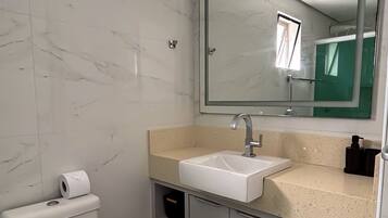 Een badkamer met toilet, wastafel, spiegel en opbergkast.