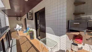 Cocina compacta con salpicadero de azulejos, horno empotrado y un pequeño comedor con mesa y sillas.