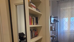 A hallway with a white radiator, wooden flooring, and a bookshelf with books. - STANZE CENTRO STORICO CAGLIARI (Cagliari)