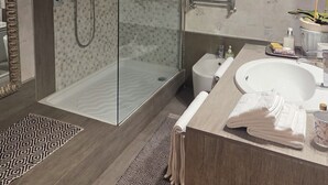 A modern bathroom with a glass-enclosed shower, a white sink, and a large mirror. - STANZE CENTRO STORICO CAGLIARI (Cagliari)