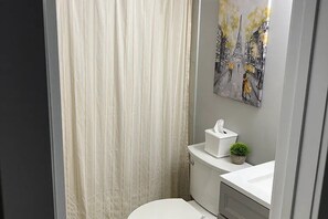 Ein Badezimmer mit Toilette, Waschbecken, Taschentuchbox und einer kleinen Pflanze.