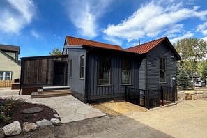 A two-story house with a front porch, a small deck, and a stone pathway leading to the entrance. - Walk to Slopes & Main St from Historic Modern House (Breckenridge)