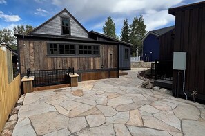 A stone patio with a wooden building, a bench, and a fenced area. - Walk to Slopes & Main St from Historic Modern House (Breckenridge)
