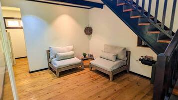 Ein Zimmer mit zwei Holzstühlen, einem kleinen Tisch, einer Wandhalterung und einer Treppe.