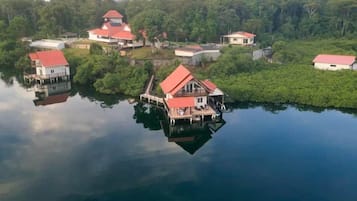 Une propriété au bord du lac comprenant plusieurs bâtiments, dont une maison imposante à toit rouge, reliés par des passerelles.