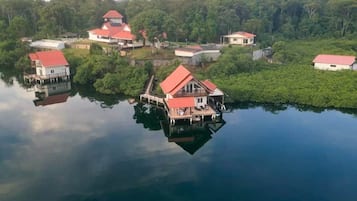 A lakeside property with multiple buildings, including a prominent house with a red roof, connected by walkways.